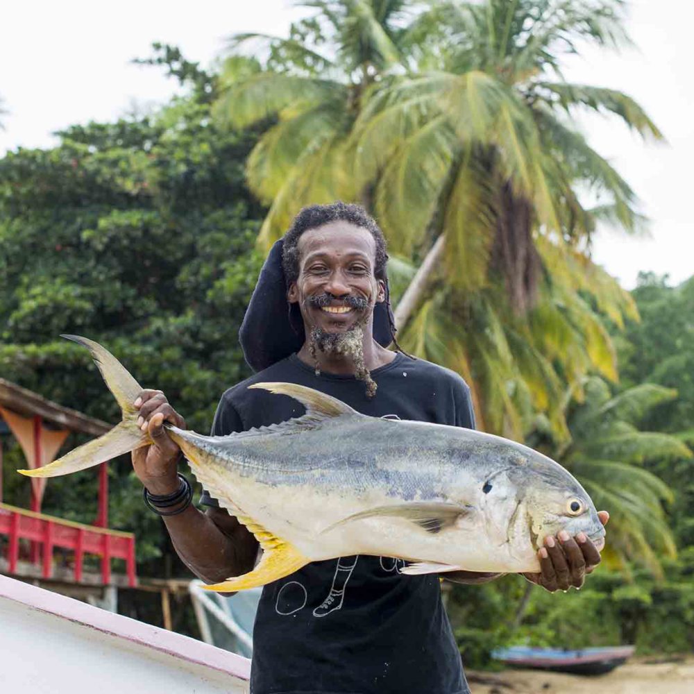 A man holds up a freshly caught Trevally fish at Castara in Tobago
